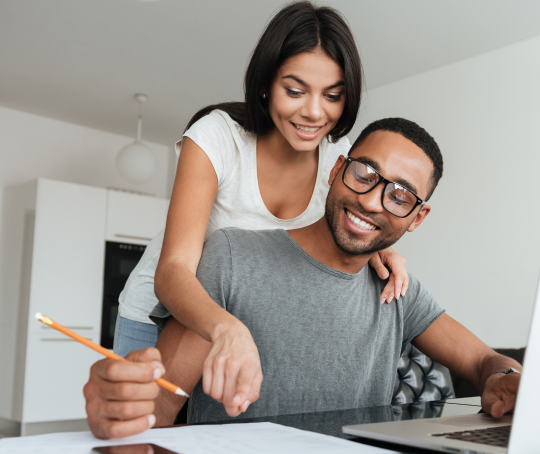 Smiling couple reviewing a document together, appearing happy and engaged